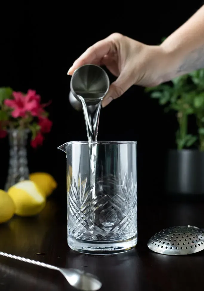 versare il gin da un jigger di metallo in un mixing glass.' loading='lazy' title=