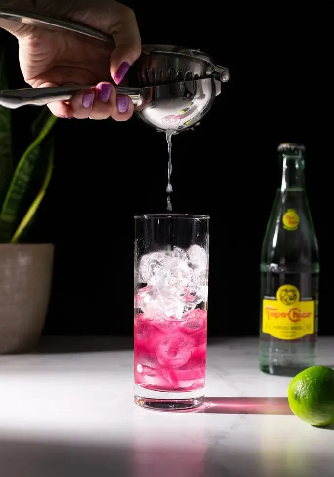 espremendo um limão em um copo alto.' loading='lazy' title=