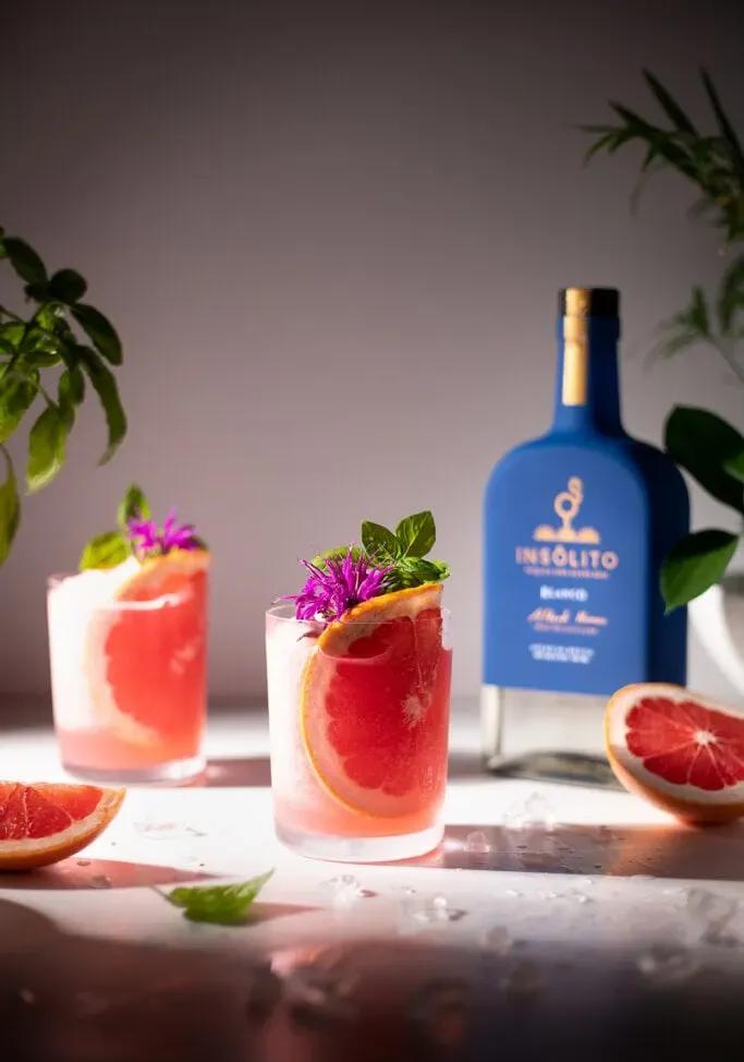 dva nápoje s plátky grapefruitu vedle láhve modré tequily.' loading='lazy' title=