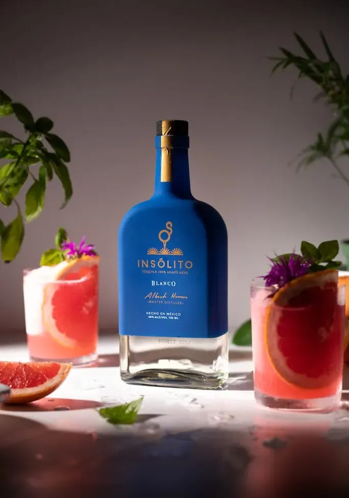 Blaue Insolito-Tequila-Flasche mit Gläsern gefrorener Palomas.' loading='lazy' title=