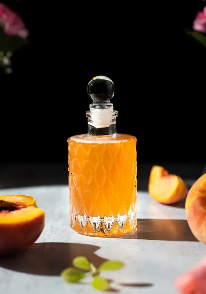 une bouteille vintage fantaisie pleine de sirop de pêche.' loading='lazy' title=