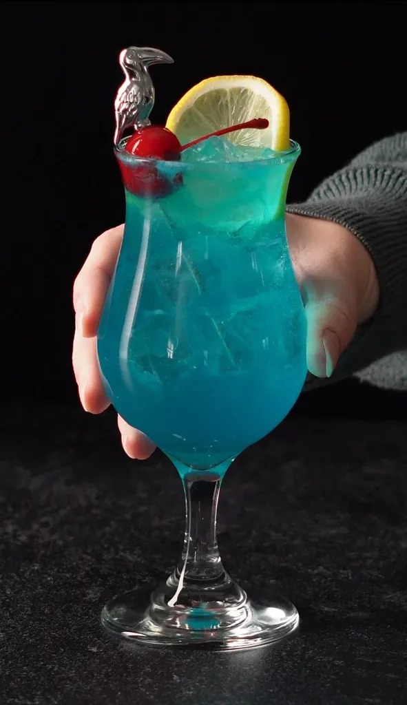 mano raccogliendo una bevanda blu tropicale.' title=