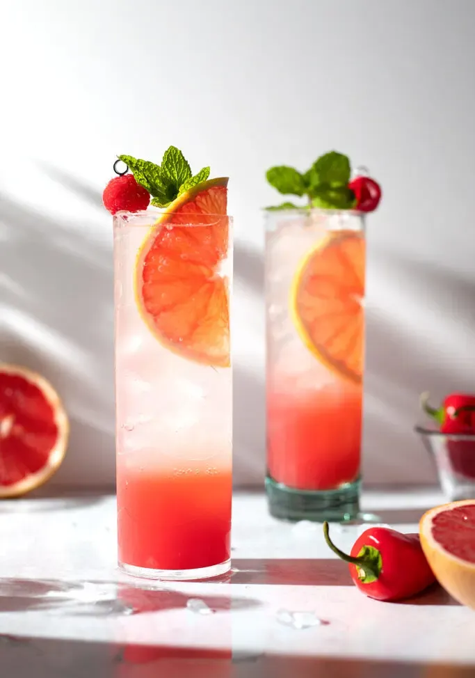 primer plano de bebidas altas de pomelo con menta y frambuesa.' title=