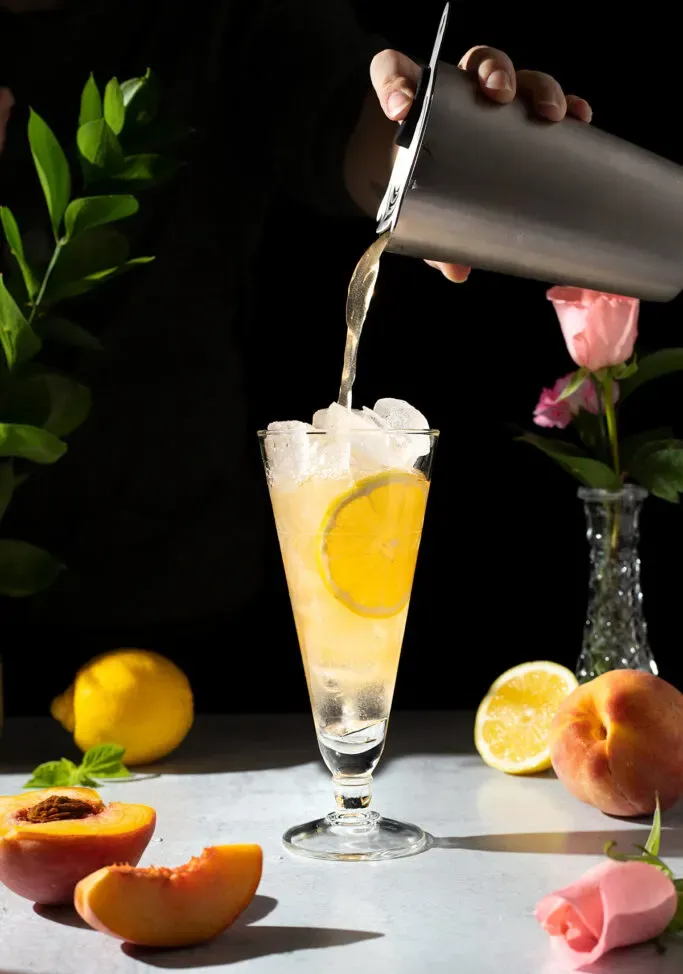 verser le liquide orange du shaker dans un verre rempli de glace.' title=