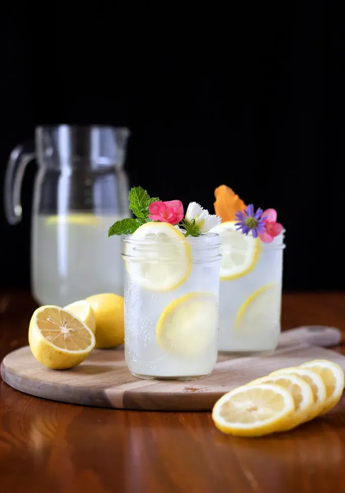 dzban i słoiki z lemoniadą z plasterkami cytryny.' title=