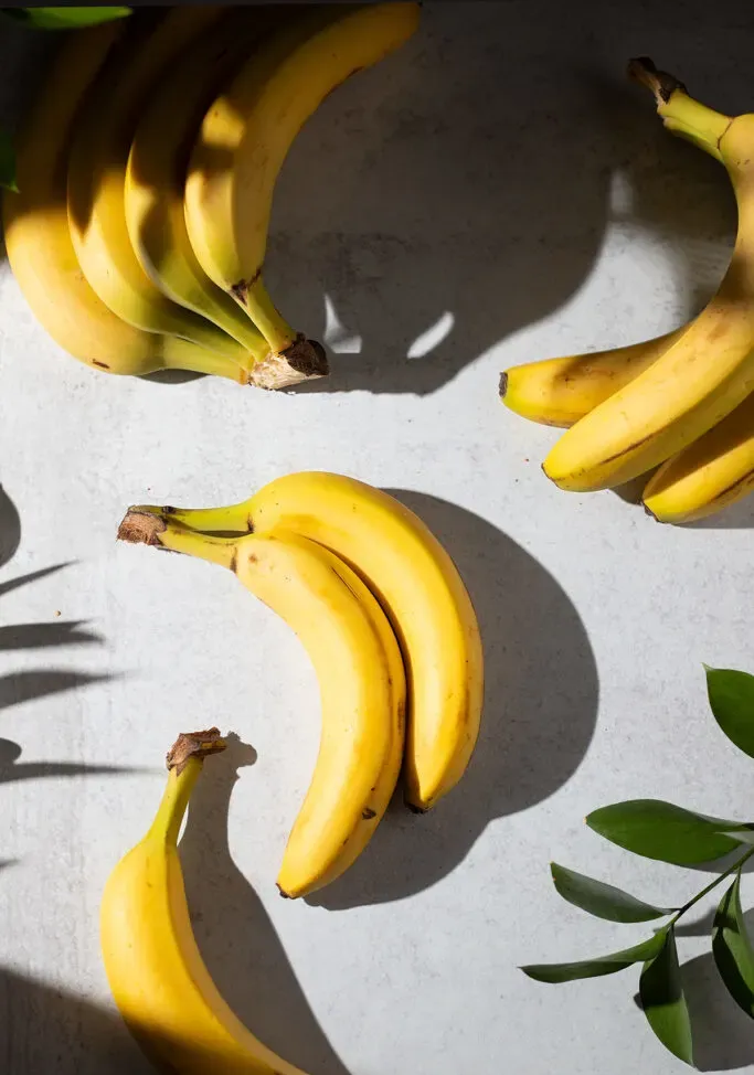 varios plátanos colocados sobre una mesa blanca.' title=