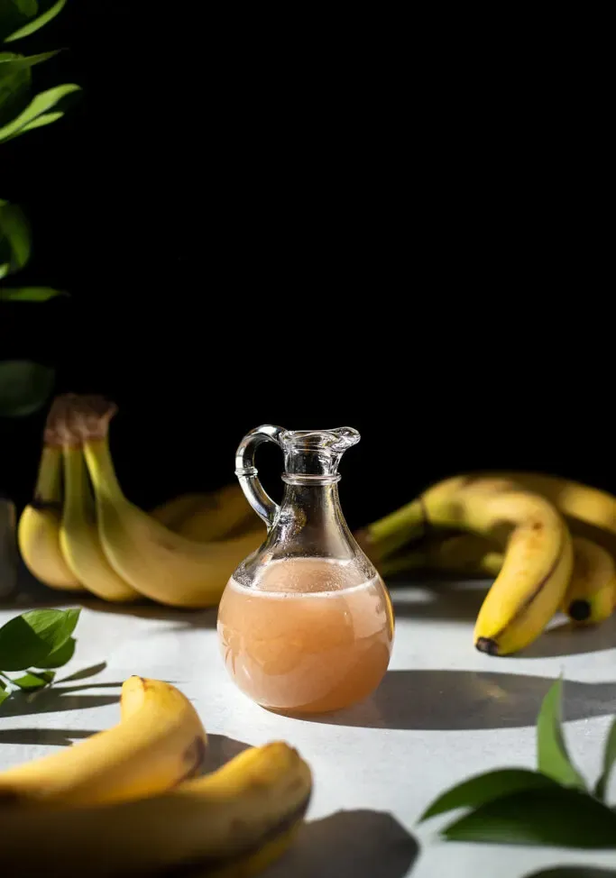 jarra de jarabe de plátano sobre fondo negro.' title=