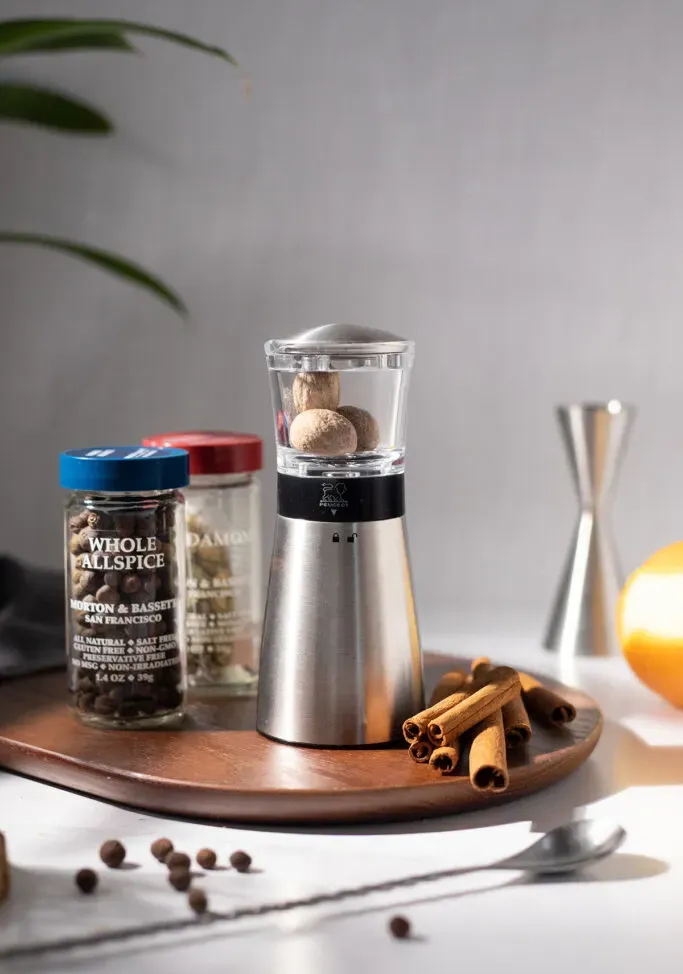 srebrna tarka do gałki muszkatołowej z całymi gałkami muszkatołowymi obok innych całych przypraw.' loading='lazy' title=