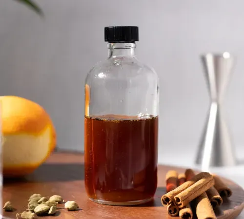 zbliżenie na butelkę aptekarską wypełnioną do połowy brązowym syropem.' title=