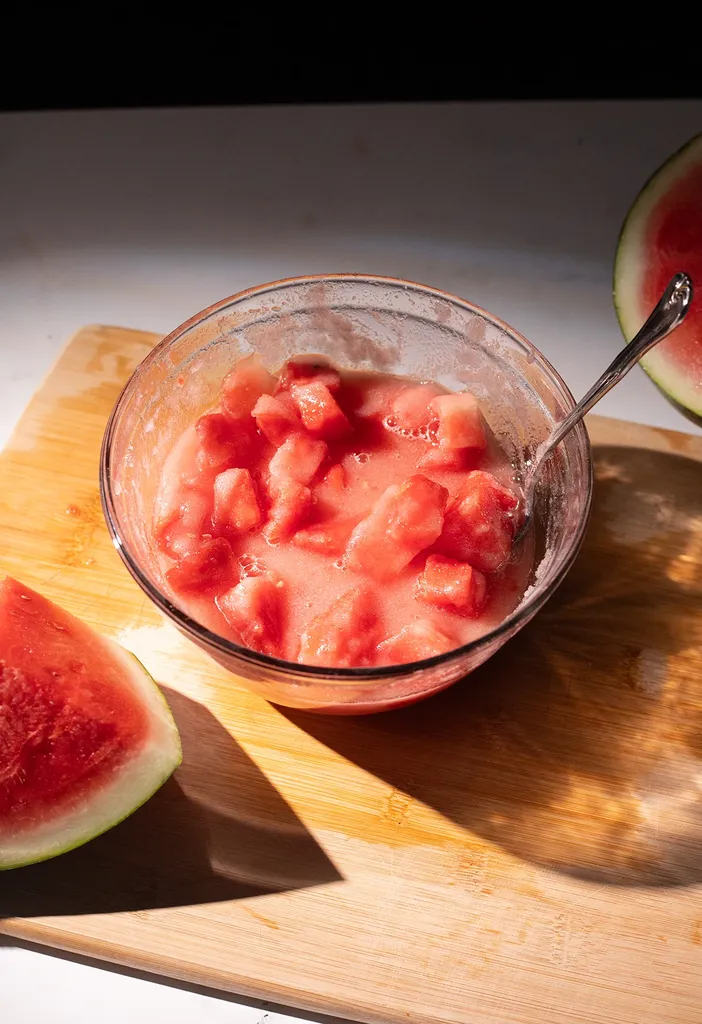 szklana miska wypełniona gęstą syropową mieszanką kawałków arbuza i cukru.' title=