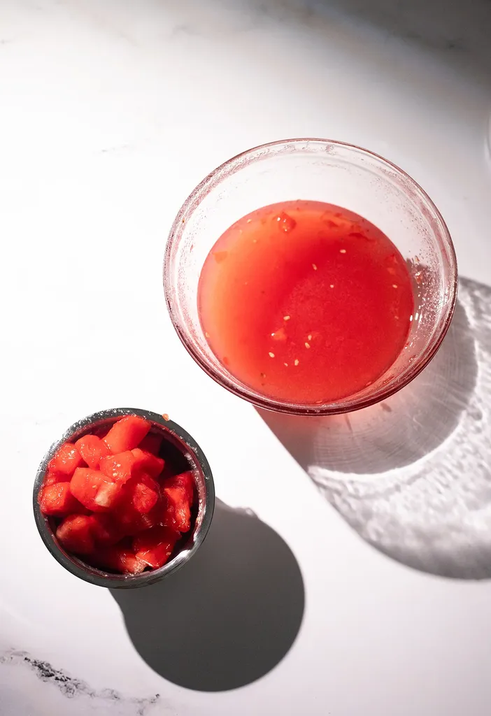 szklana butelka jasnego czerwono-różowego płynu obok arbuza.' title=