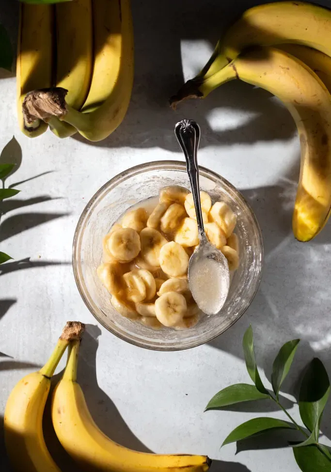 una ciotola di fette di banana sciroppate accanto alle banane.' loading='lazy' title=