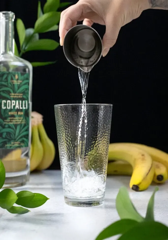 versare il rum bianco da un misurino in uno shaker.' title=