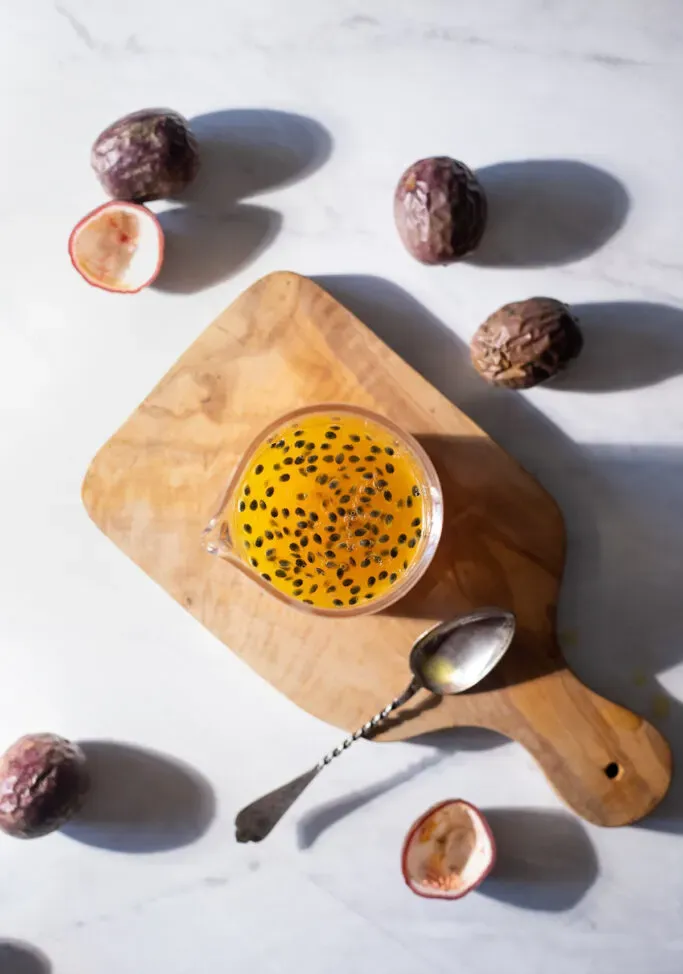 עיסת פסיפלורה בצנצנת זכוכית על קרש חיתוך.' loading='lazy' title=