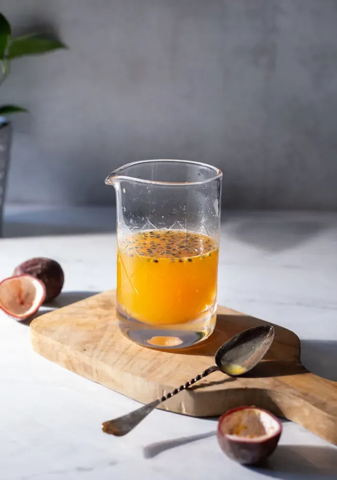 צנצנת זכוכית מלאה בעיסת פסיפלורה ליד כף.' loading='lazy' title=