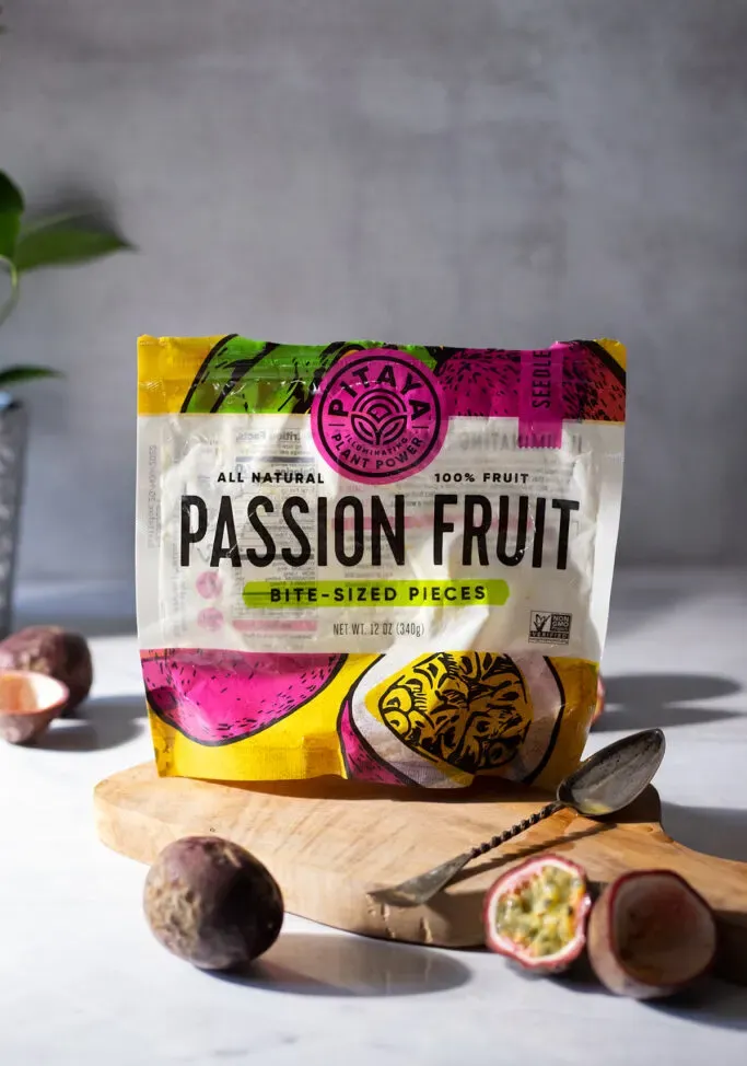 שקית מחית פסיפלורה קפואה לצד פסיפלורה טריים.' loading='lazy' title=