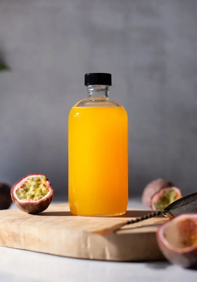 בקבוק זכוכית של סירופ צהוב עז לצד פסיפלורה.' loading='lazy' title=