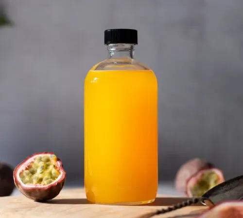 בקבוק זכוכית של סירופ צהוב עז לצד פסיפלורה.' title=