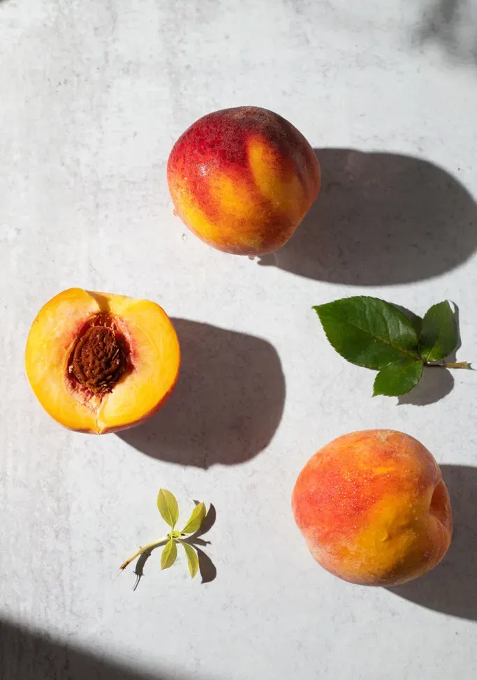 흰색 테이블에 세 개의 노란 복숭아입니다.' loading='lazy' title=