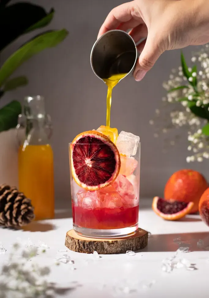 Gießen Sie leuchtend gelben Kurkuma-Sirup mit Eis und rotem Blutorangensaft in das Glas.' loading='lazy' title=