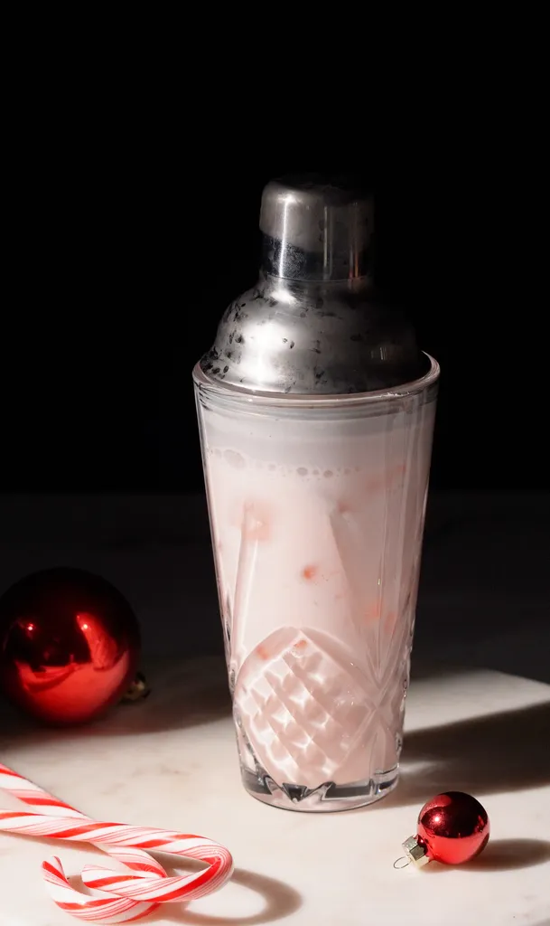 Cocktailshaker aus Glas, gefüllt mit einer blassrosa, cremigen Flüssigkeit.' loading='lazy' title=