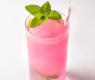 분홍색 얼음 구체와 민트 장식이 있는 긴 유리잔.' title=