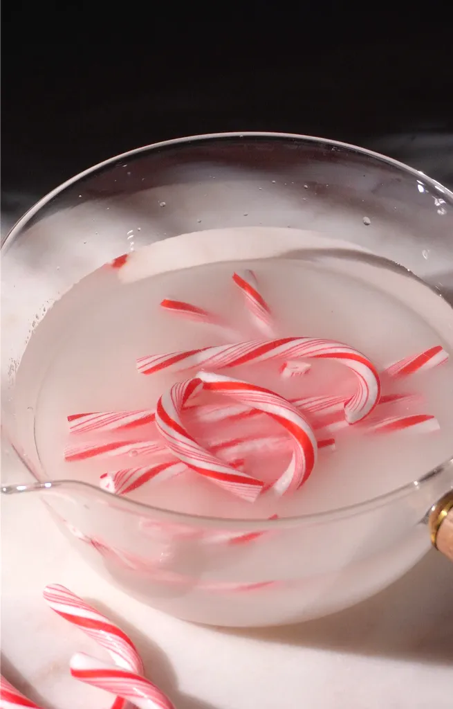 חתיכות שבורות של קני ממתקים אדומים ולבנים בסיר זכוכית.' loading='lazy' title=