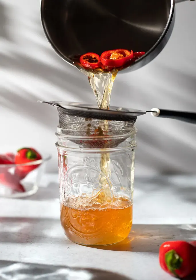 coar pimentas do xarope de mel em um frasco de vidro' title=