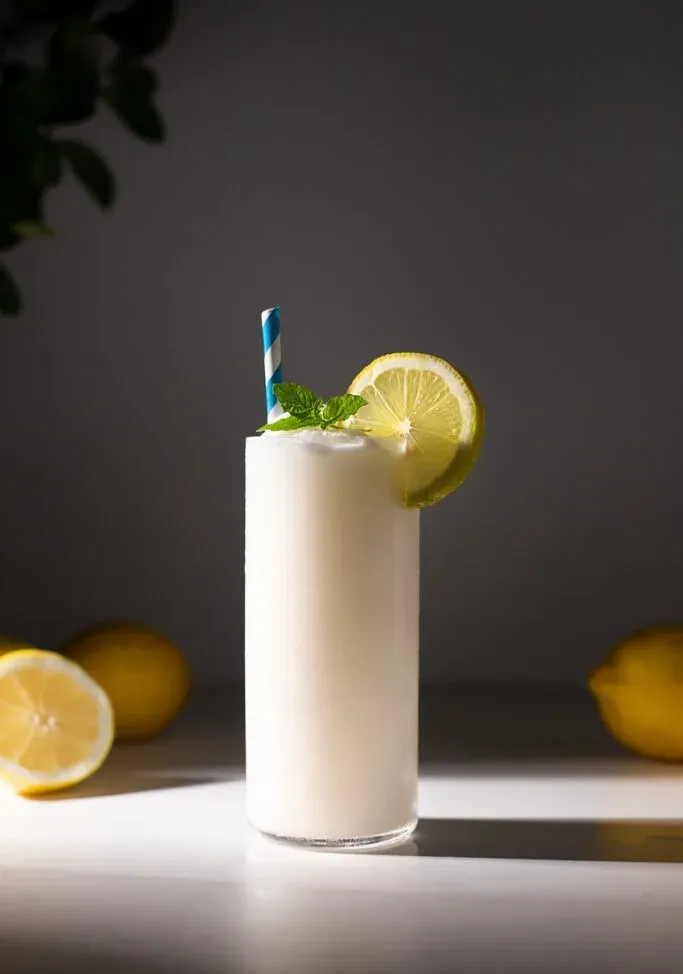 um copo de limonada batida com canudo de papel azul.' title=