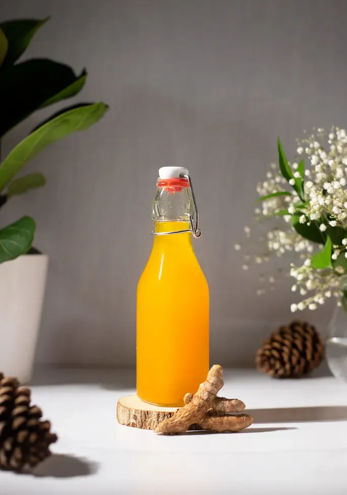 fľaša s hojdacím vrchom naplnená jasne pomarančovým sirupom.' title=