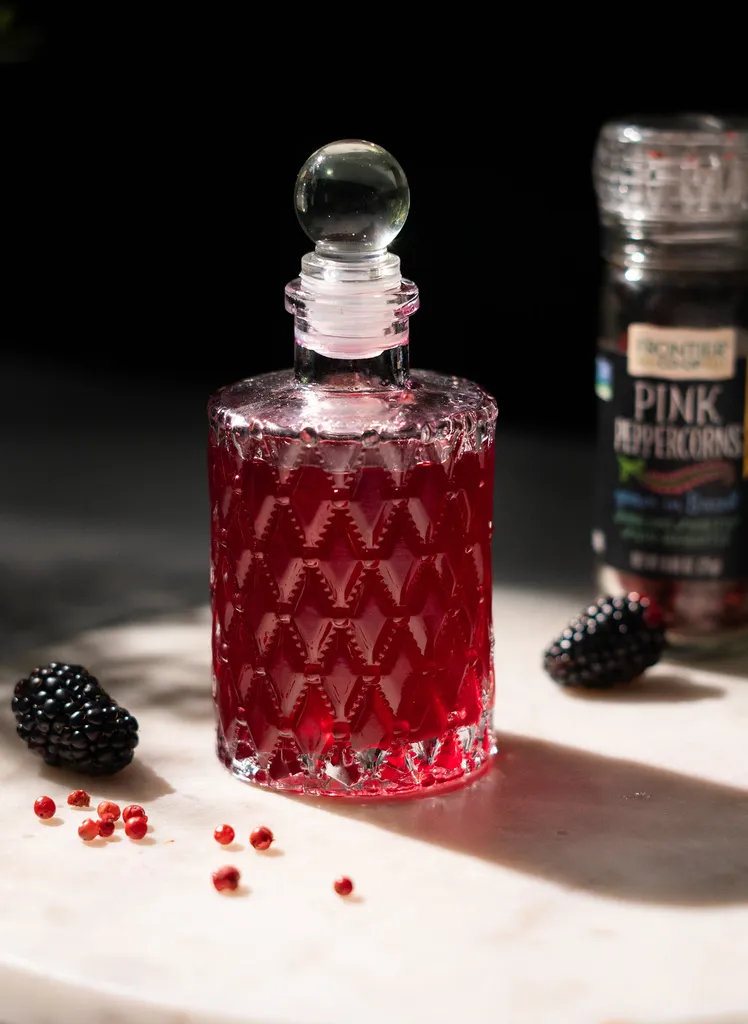 ピンクペッパーのスパイス瓶の隣にある赤い液体の小さなガラス瓶。' loading='lazy' title=