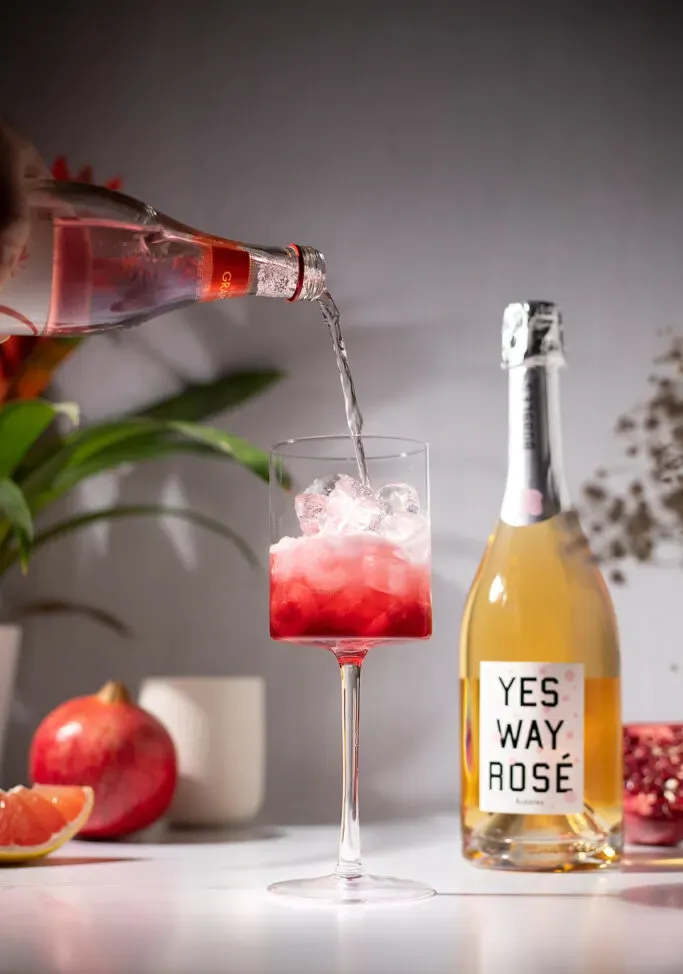 verser du soda au pamplemousse dans un verre à vin rempli de glace.' title=