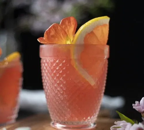 růžový koktejl ve sklenici rocks s plátkem růžového grapefruitu' title=