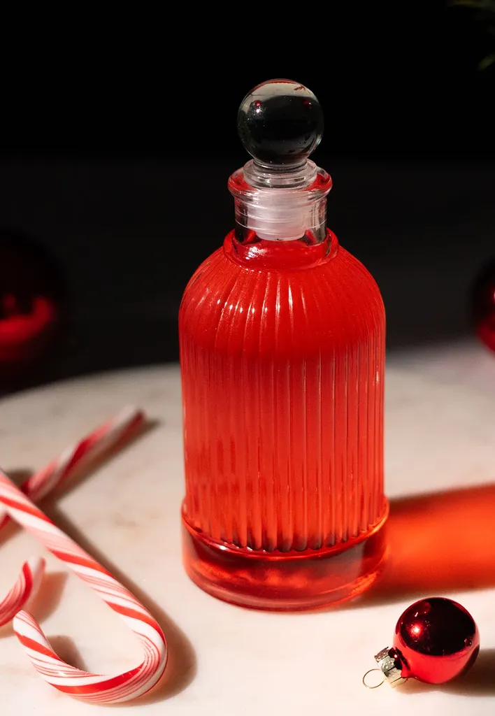 petite bouteille en verre de sirop rouge à côté des cannes de bonbon.' title=