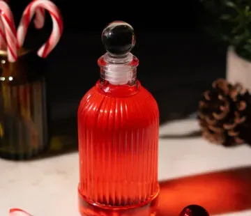 petite bouteille en verre remplie de liquide rouge.' title=