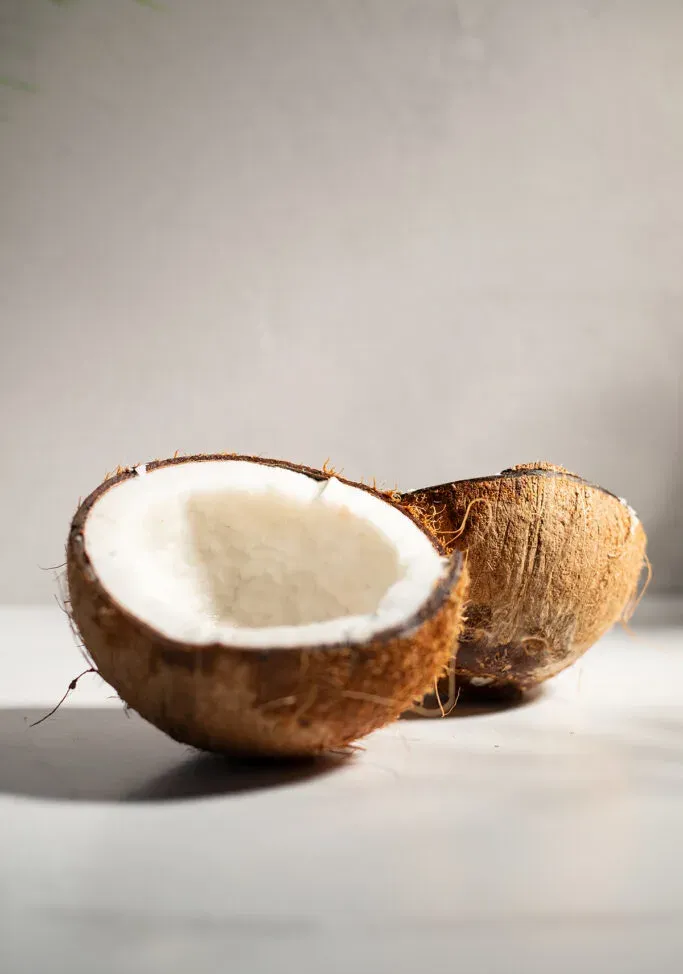dvě poloviny kokosu na bílém stole.' loading='lazy' title=