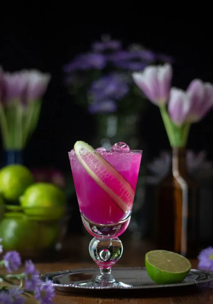 un cocktail rosa con nastro di nastro di cetriolo.' title=