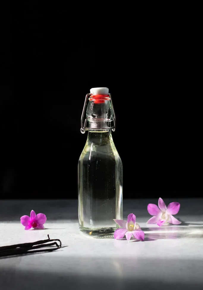 fľaša číreho vanilkového sirupu s orchideami.' title=