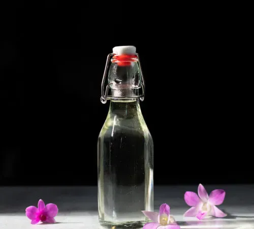fľaša číreho vanilkového sirupu s orchideami.' title=