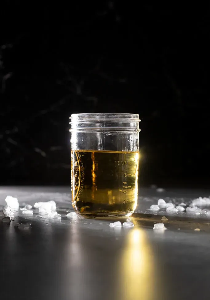un frasco de vidrio lleno de ron con infusión de arce de color amarillo pálido.' loading='lazy' title=
