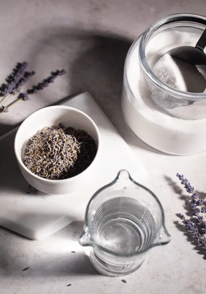 קערת לבנדר מיובש עם קערת סוכר וכוס מים.' loading='lazy' title=