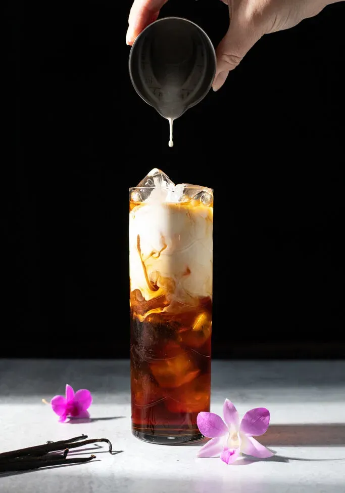 una goccia di panna che cade nel caffè freddo.' loading='lazy' title=