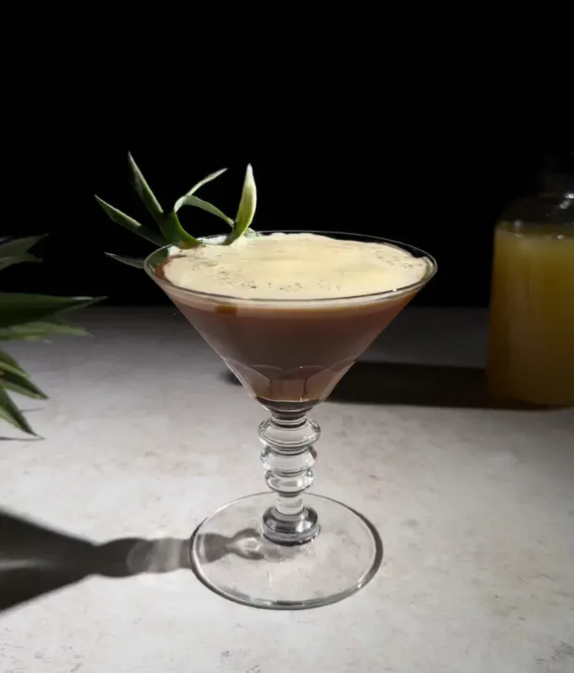 cocktail aigre-espresso brun dans un verre à martini.' title=