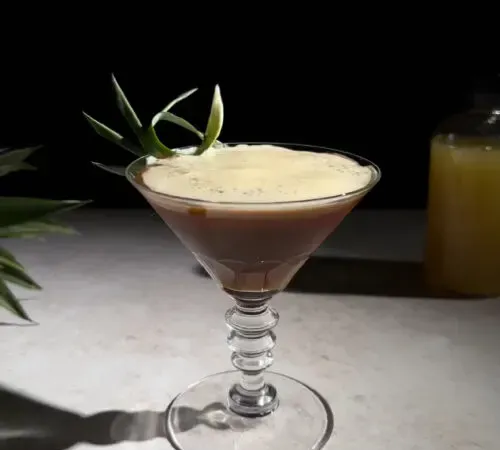 cocktail aigre-espresso brun dans un verre à martini.' title=