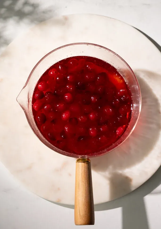 빨간 시럽과 크랜베리를 채운 유리 냄비.' title=