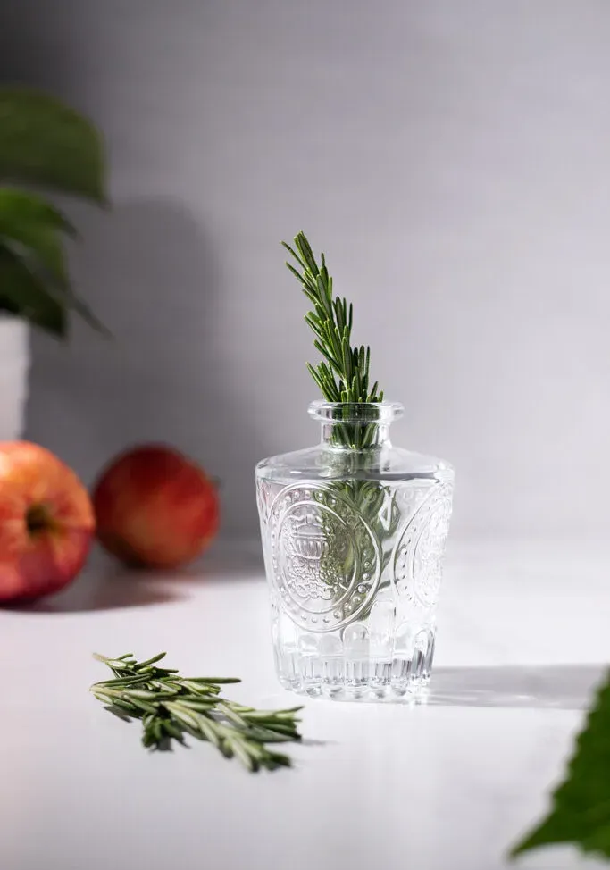 mały szklany wazon z dużą gałązką świeżego rozmarynu.' loading='lazy' title=
