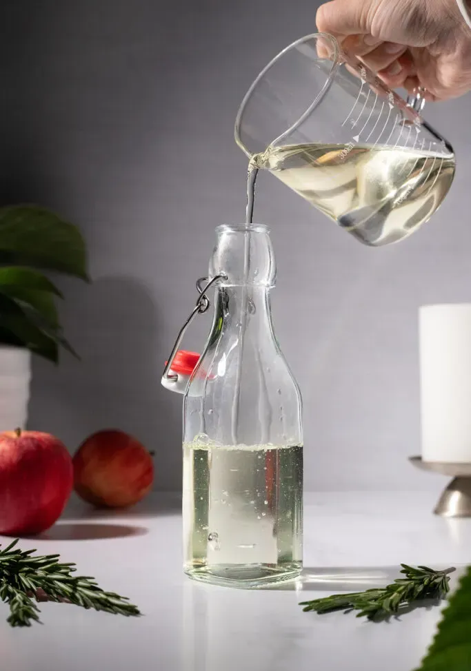 wlewając syrop rozmarynowy do butelki z uchylną górną częścią.' loading='lazy' title=