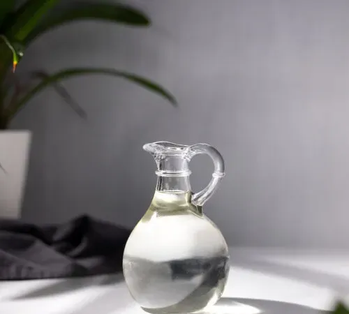 una piccola brocca di vetro piena di liquido trasparente.' title=