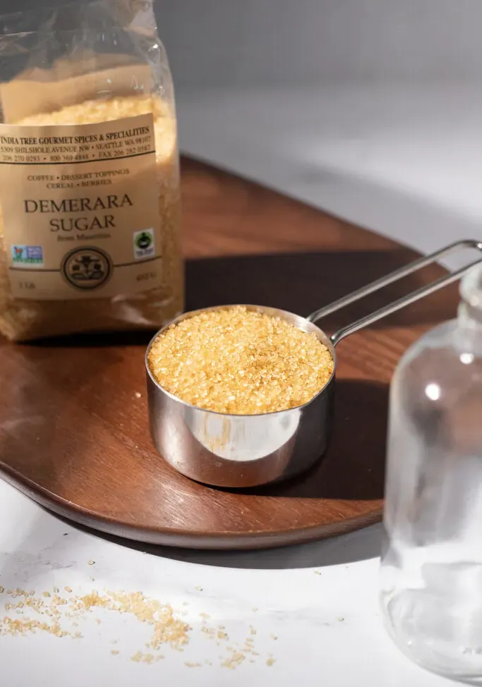 un misurino di metallo pieno di cristalli di zucchero di canna demerara.' title=