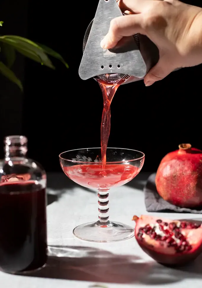 vertiendo un cóctel rojo en una copa cupé' loading='lazy' title=
